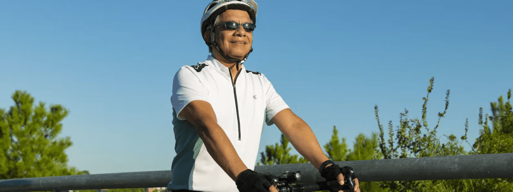 Man riding a bicycle in the park, wearing sunglasses and a helmet